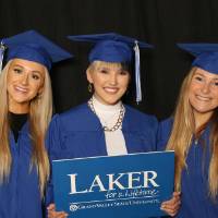 three friends with pom pom and Laker for a Lifetime sign